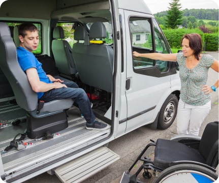 Woman assisting handicapped individual into a van