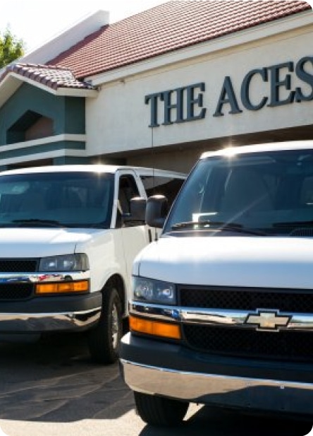 Vans parked in a row in front of an Aces campus